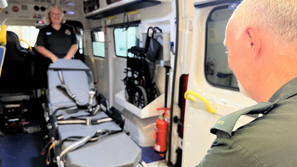 A lady and a gentleman loading a transport bed on to a transport vehicle. 
